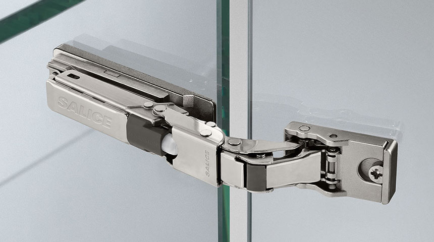 Close-up of a nickel-plated Salice hinge mounted on the edge of glass with the Salice logo visible