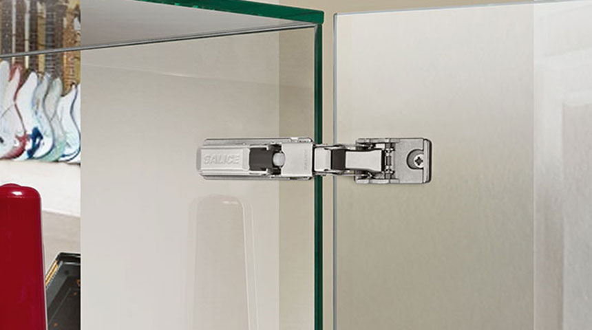 Salice hinge mounted on a glass door of a cabinet with interior furnishings in the background