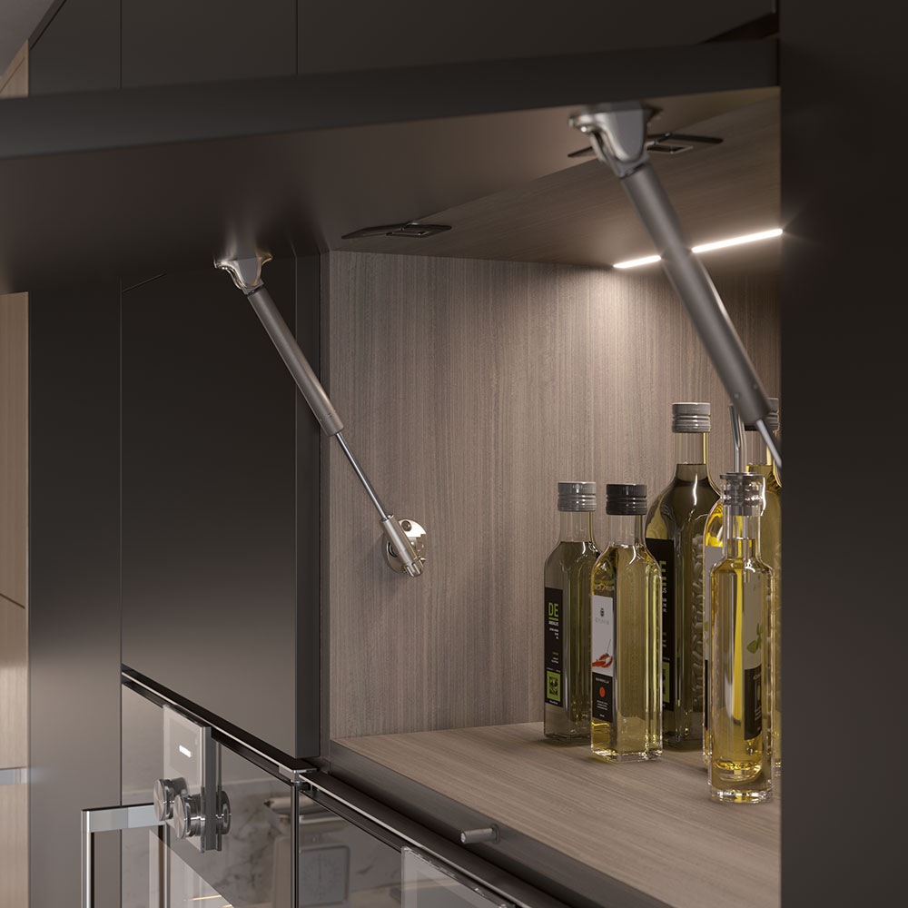 Open upper cabinet with two Kraby lift-up gas springs installed and bottles inside the cabinet