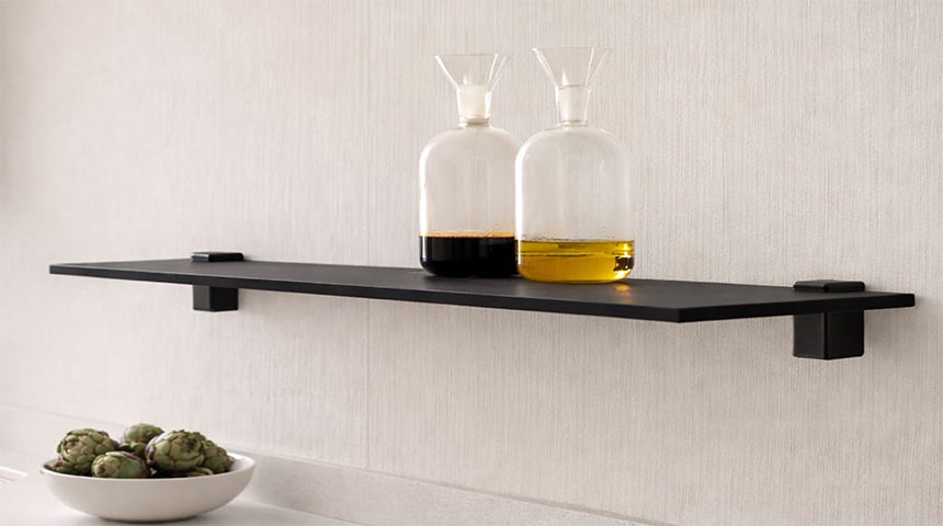 Black wall-mounted shelf with black shelf supports and two glass bottles with liquid.