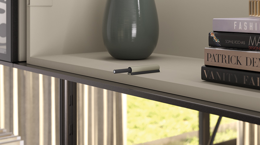 K Push Tech Texture trycklås monterat på en hyllplan i en möbel med vas och böcker.